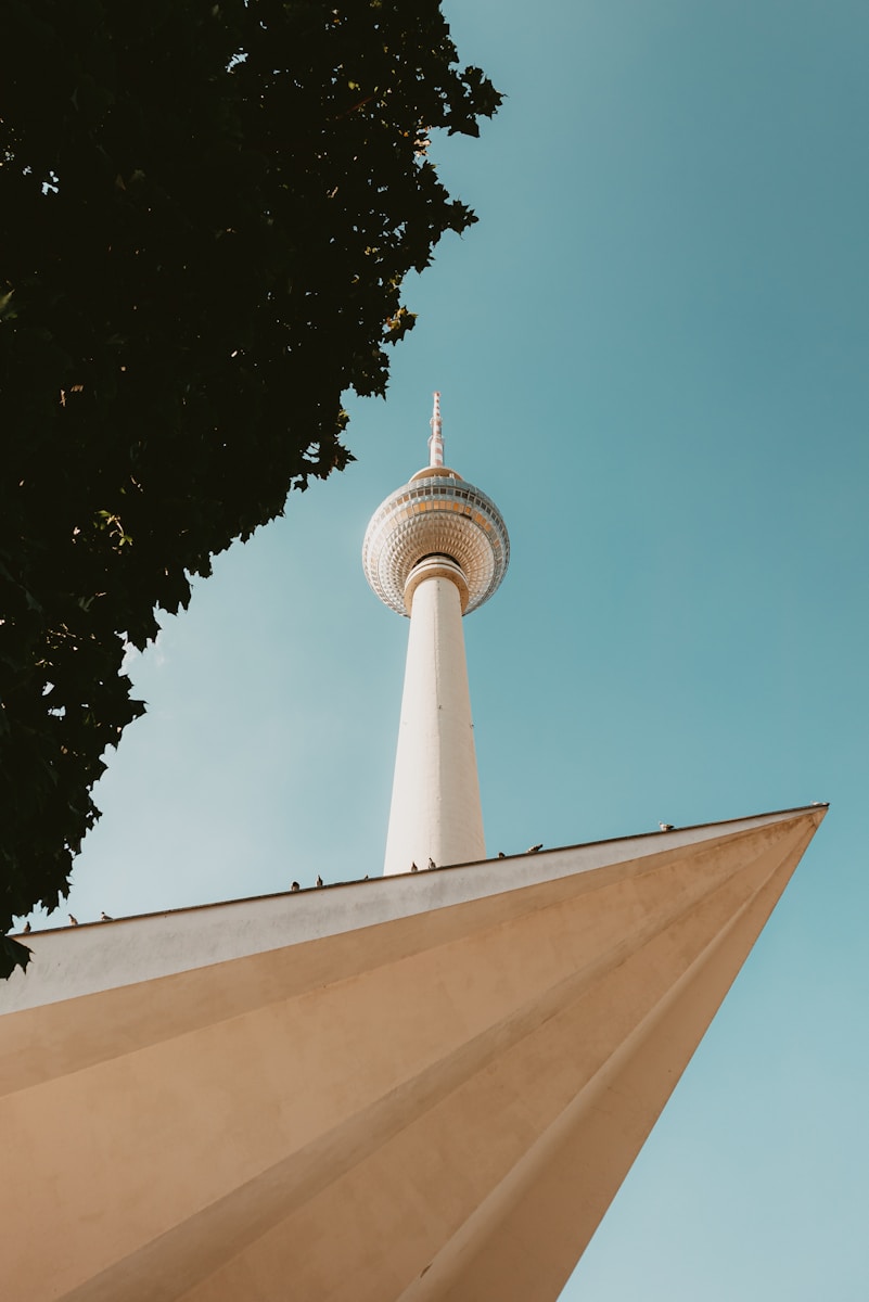 The berlin TV tower stands tall against the blue sky.
